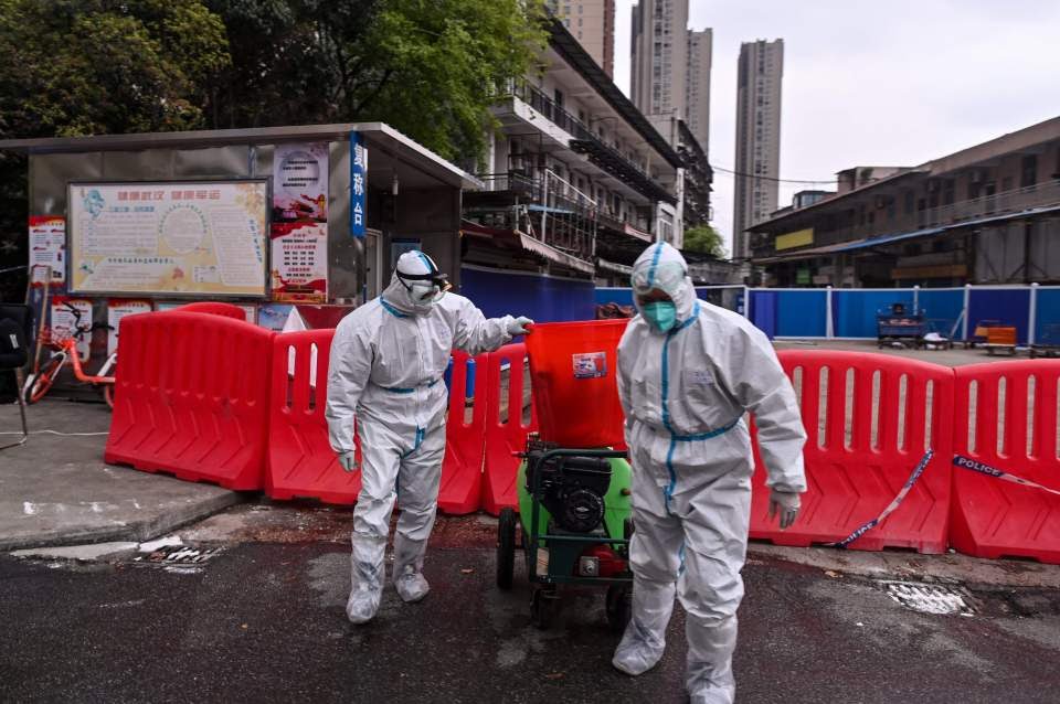 Workers wearing protective suits walk next to Huanan Seafood Wholesale Market in Wuhan, believed to be ground zero of the coronavirus