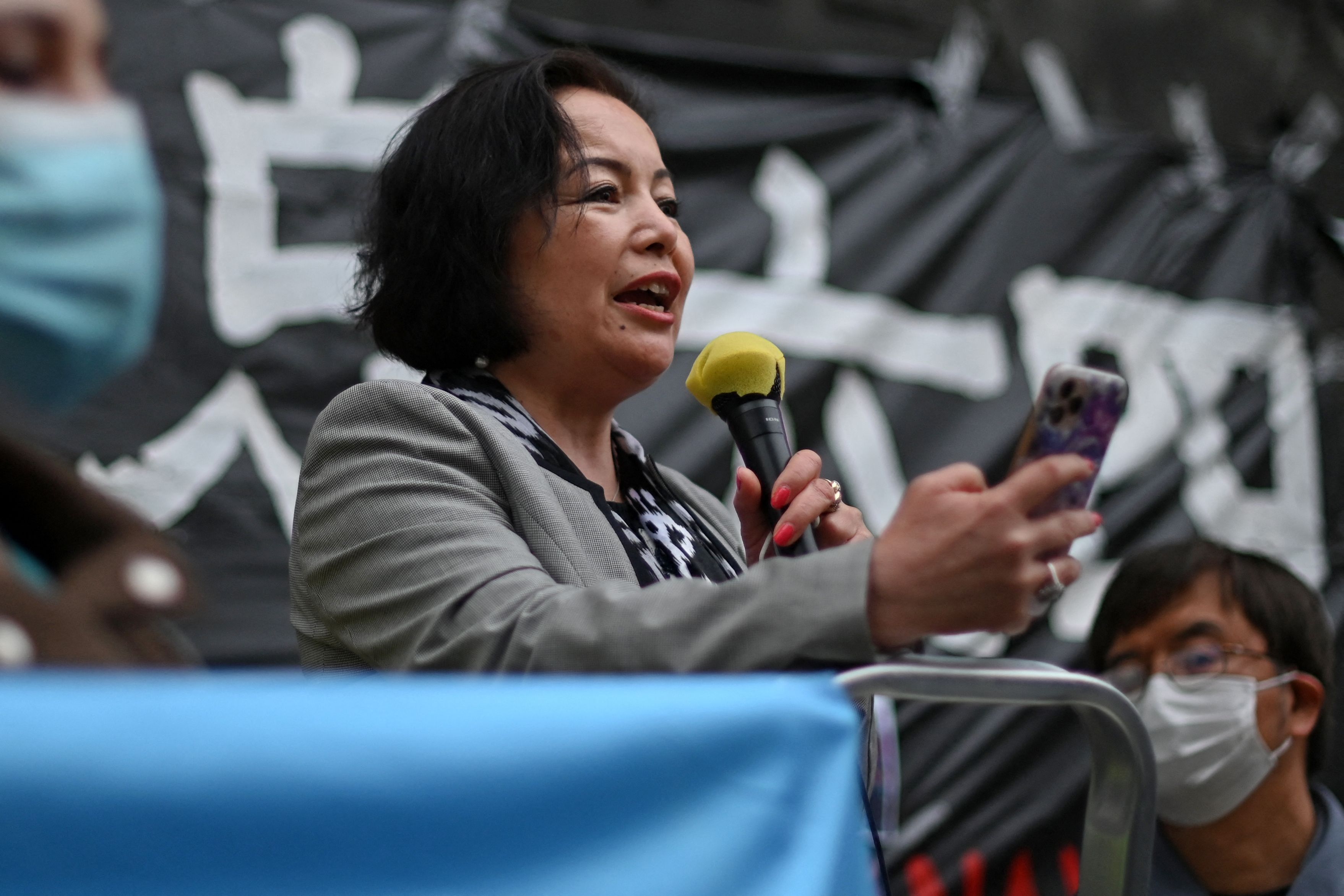 Photo of a person speaking into a mic at an outdoor vigil