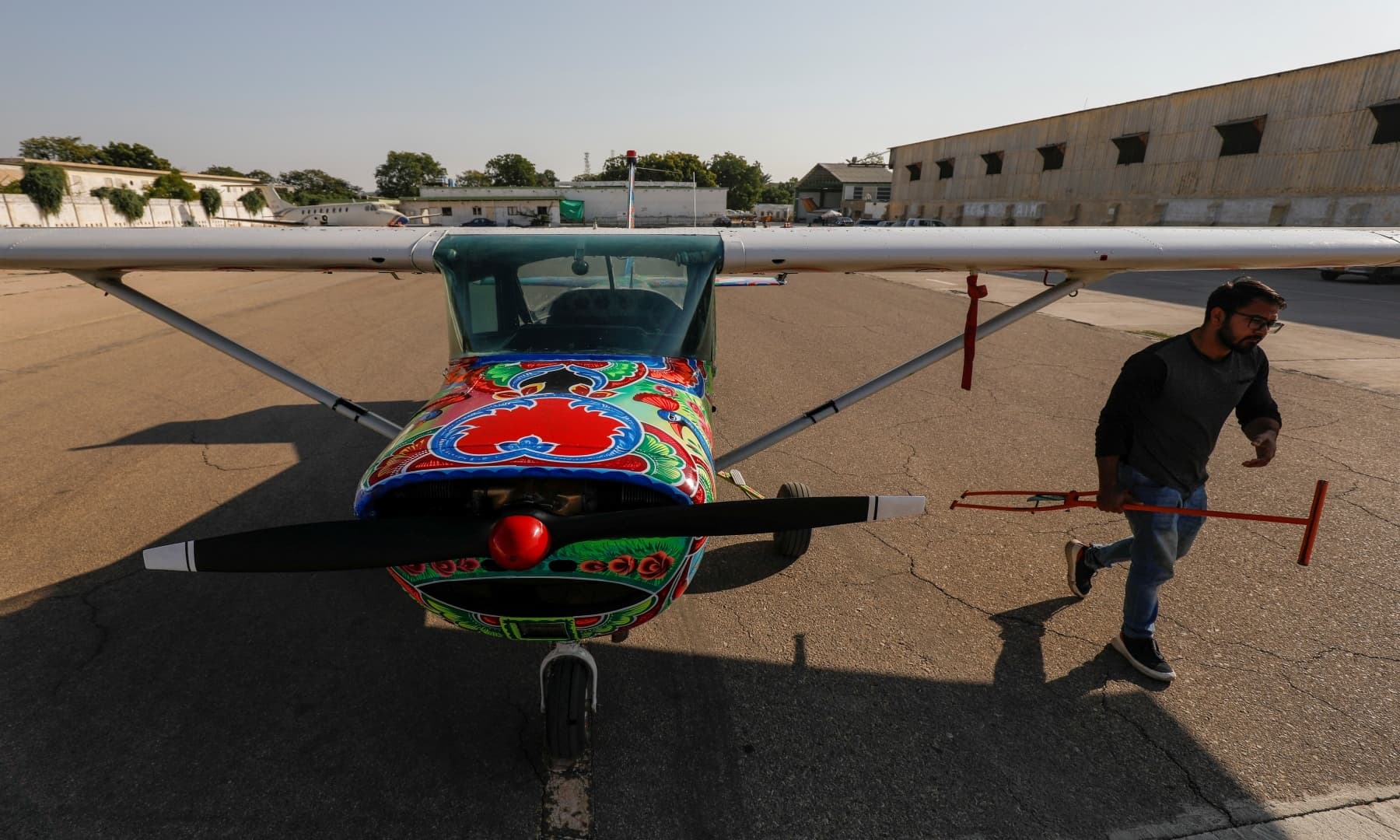 A technician walks past a two-seater Cessna aircraft painted with Pakistani truck art at Jinnah International Airport, Karachi, Dec 30, 2020. — Reuters