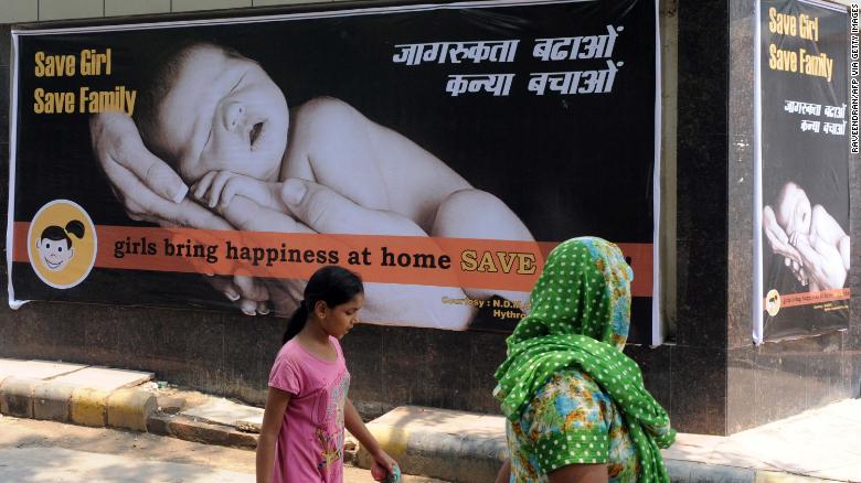 An Indian woman and child walk past a billboard in New Delhi on July 9, 2010, encouraging the birth of girls.