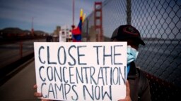 A protester holds up a Close The Concentration Camps Now sign after marching across the Golden Gate Bridge during a demonstration against the 2022 Beijing Winter Olympic Games, in San Francisco, California on Feb. 3, 2022.
