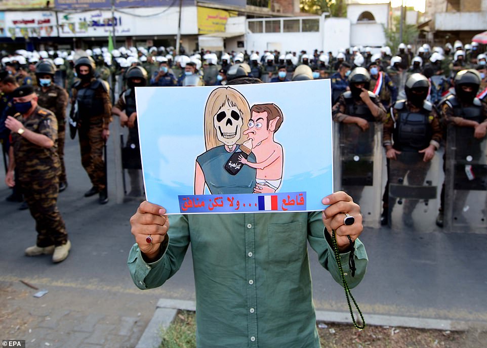 A protester in Iraq carries a portrait of Macron and his wife, denouncing the French President for disrespecting the Prophet