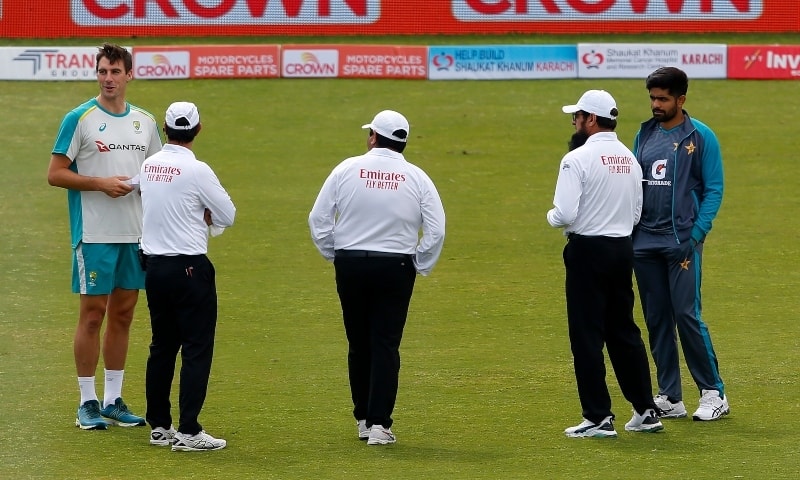 Umpires chat with Pakistan skipper Babar Azam, right, and his Australian counterpart Pat Cummins, left, after examining the ground before the start of the 4th day play of the first cricket Test match between Pakistan and Australia at the Rawalpindi Stadium on Monday. — AP