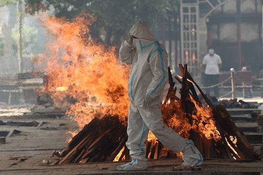 Family member wearing PPE performs last rites of a COVID-19 victim at Nigambodh Ghat crematorium, in New Delhi. (PTI)