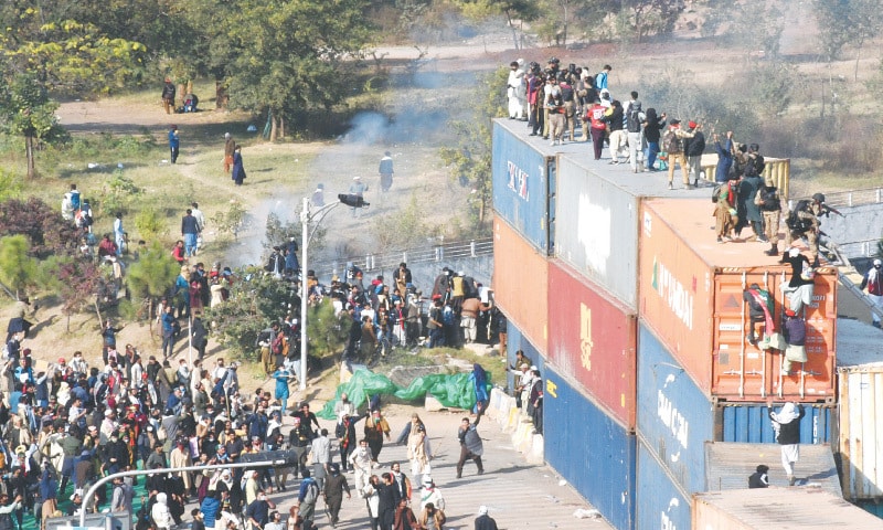 ISLAMABAD: PTI supporters climb containers blocking access to D-Chowk, as military personnel deployed atop them try to stop protesters from entering the Red Zone, on Tuesday.— Mohammad Asim / White Star