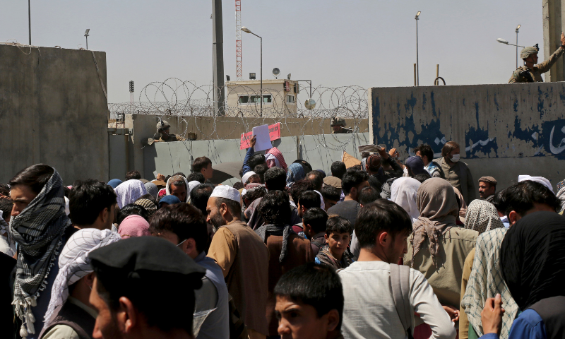 US soldiers stand inside the airport wall as hundreds of people gather near an evacuation control checkpoint on the perimeter of the Hamid Karzai International Airport, in Kabul, Afghanistan, on Thursday. — AP