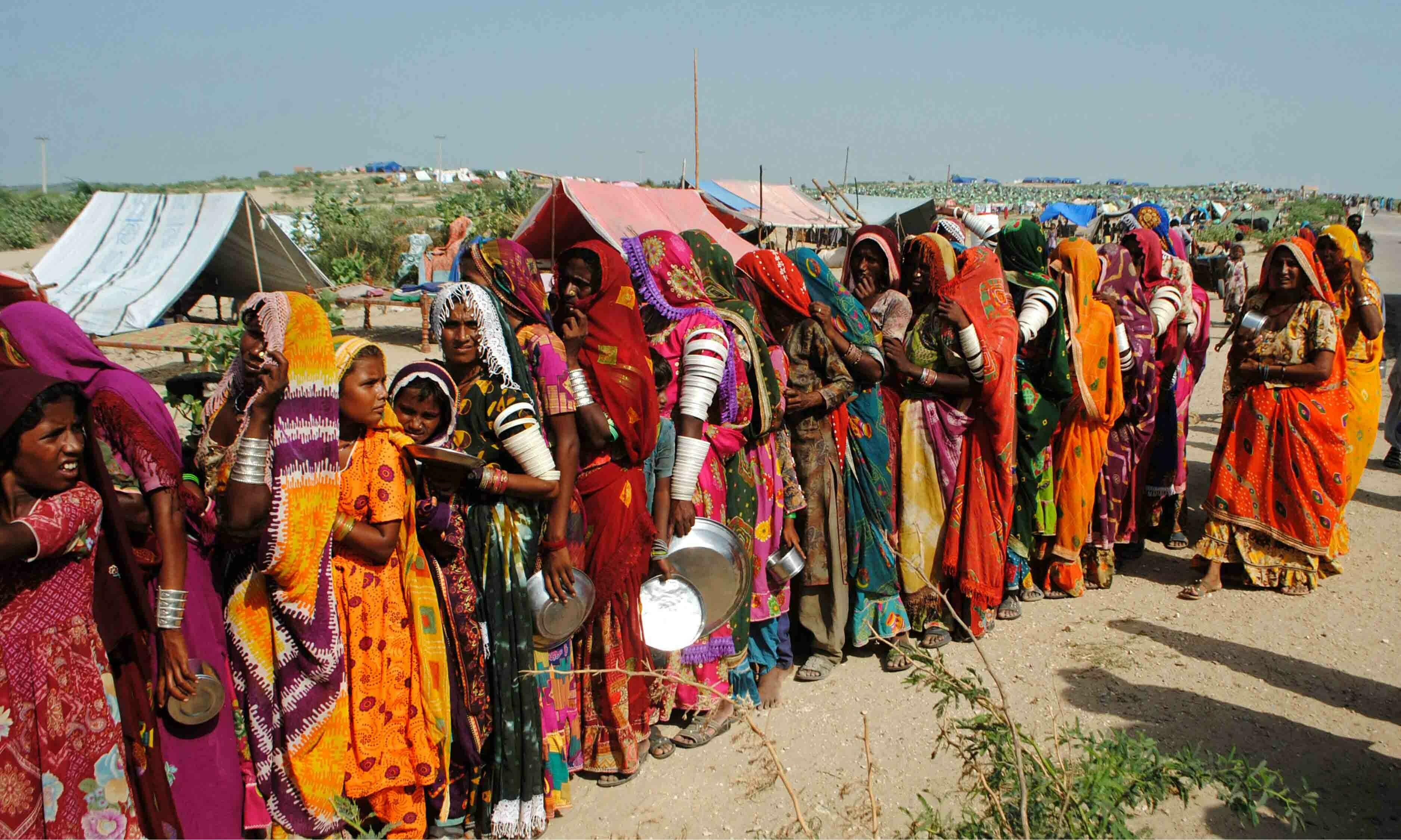 <p>Internally displaced people gather to receive free food near their makeshift camp in the flood-hit Chachro of Sindh province on September 19. — AFP</p>