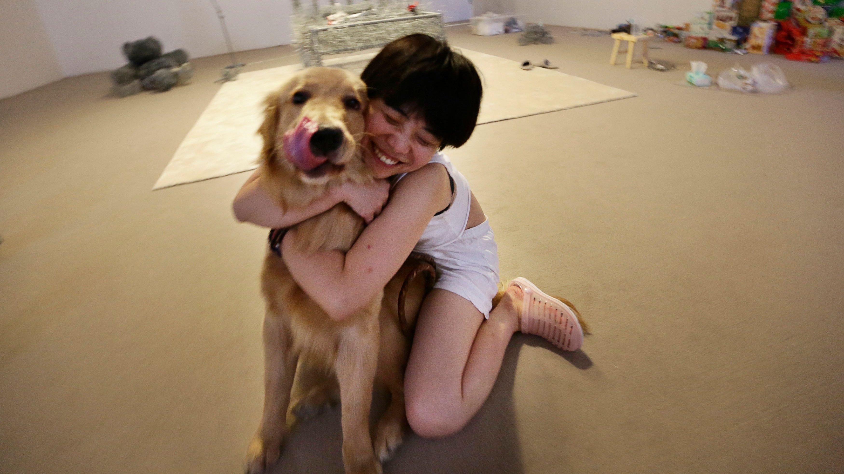 Chinese artist Zhou Jie hugs her pet dog Dan Dan, which visited her, at Beijing Art Now Gallery, in Beijing August 11, 2014. Zhou started her art project titled 36 Days on August 9, in which she would live inside an exhibition hall with an unfinished iron wire bed, some iron wire sculptures in the shape of stuffed animal dolls, a certain amount of food and her mobile phone for 36 days. According to Zhou, the entire process is open to visitors and she may also interact with them. Picture taken August 11, 2014.