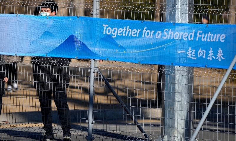 A person looks through the fence at the closed-loop area for Olympics personnel on the Olympic Green near at the 2022 Winter Olympics on February 1. — AP