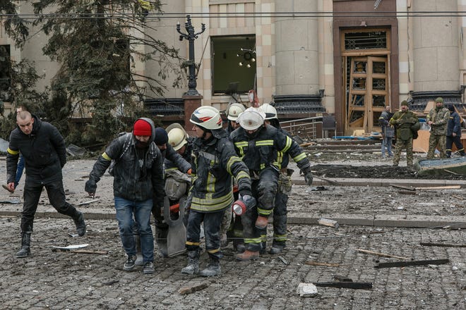 Ukrainian emergency service personnel carry a body of a victim out of the damaged City Hall building following shelling in Kharkiv, Ukraine, Tuesday, March 1, 2022.