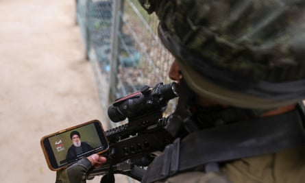 An Israeli soldier watches Hassan Nasrallah’s speech on his phone