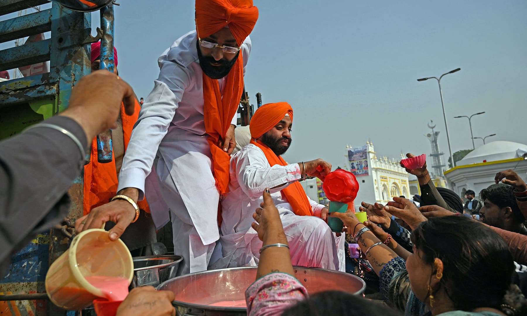 Sikh devotees distribute sweet drinks during a religious procession on the occasion of the birth anniversary of Guru Nanak Dev in Nankana Sahib on November 19. — AFP