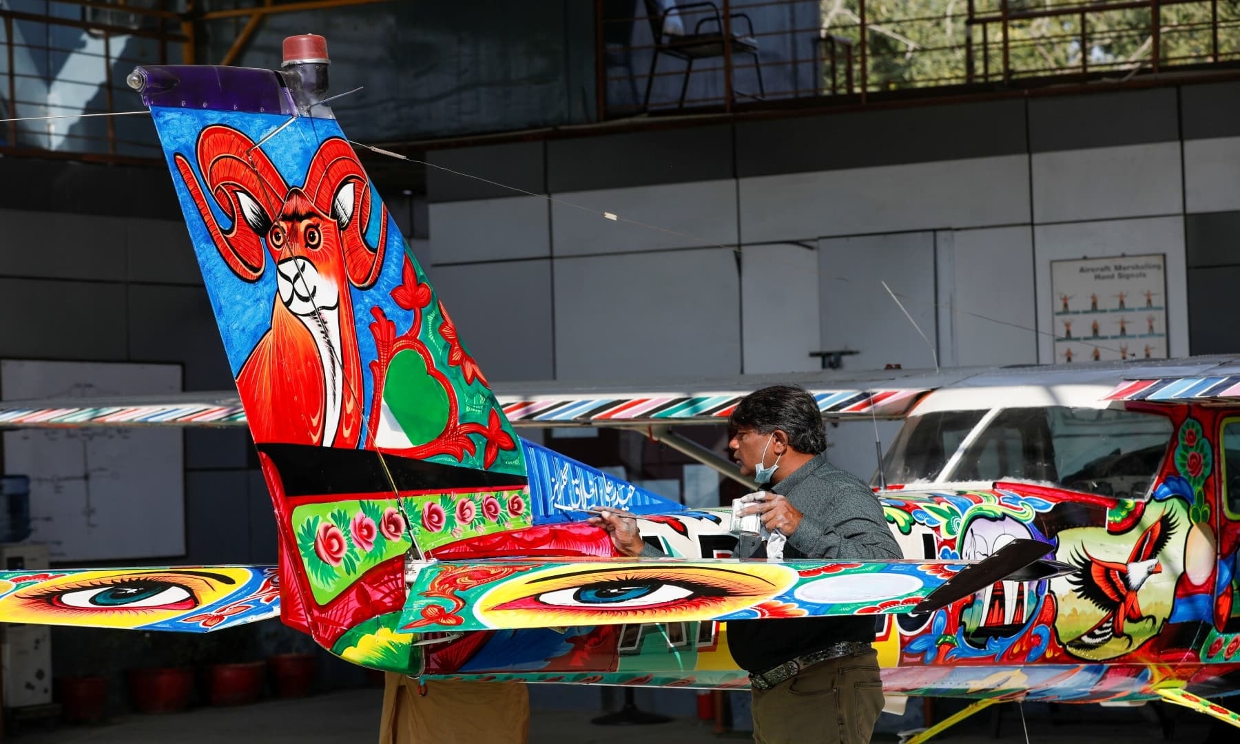 Haider Ali decorates a two-seater Cessna aircraft with Pakistani truck art at Jinnah International Airport, Karachi, Dec 30, 2020. — Reuters