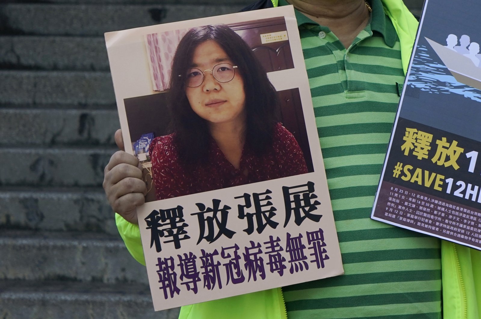 A pro-democracy activist holds placards with the picture of Chinese citizen journalist Zhang Zhan outside the Chinese central government's liaison office, in Hong Kong, Dec. 28, 2020. (AP Photo)