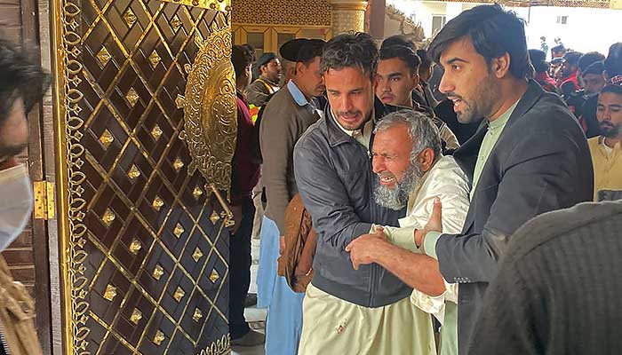 People help a mourner at the site of a mosque blast inside the police headquarters in Peshawar on January 30, 2023. — AFP