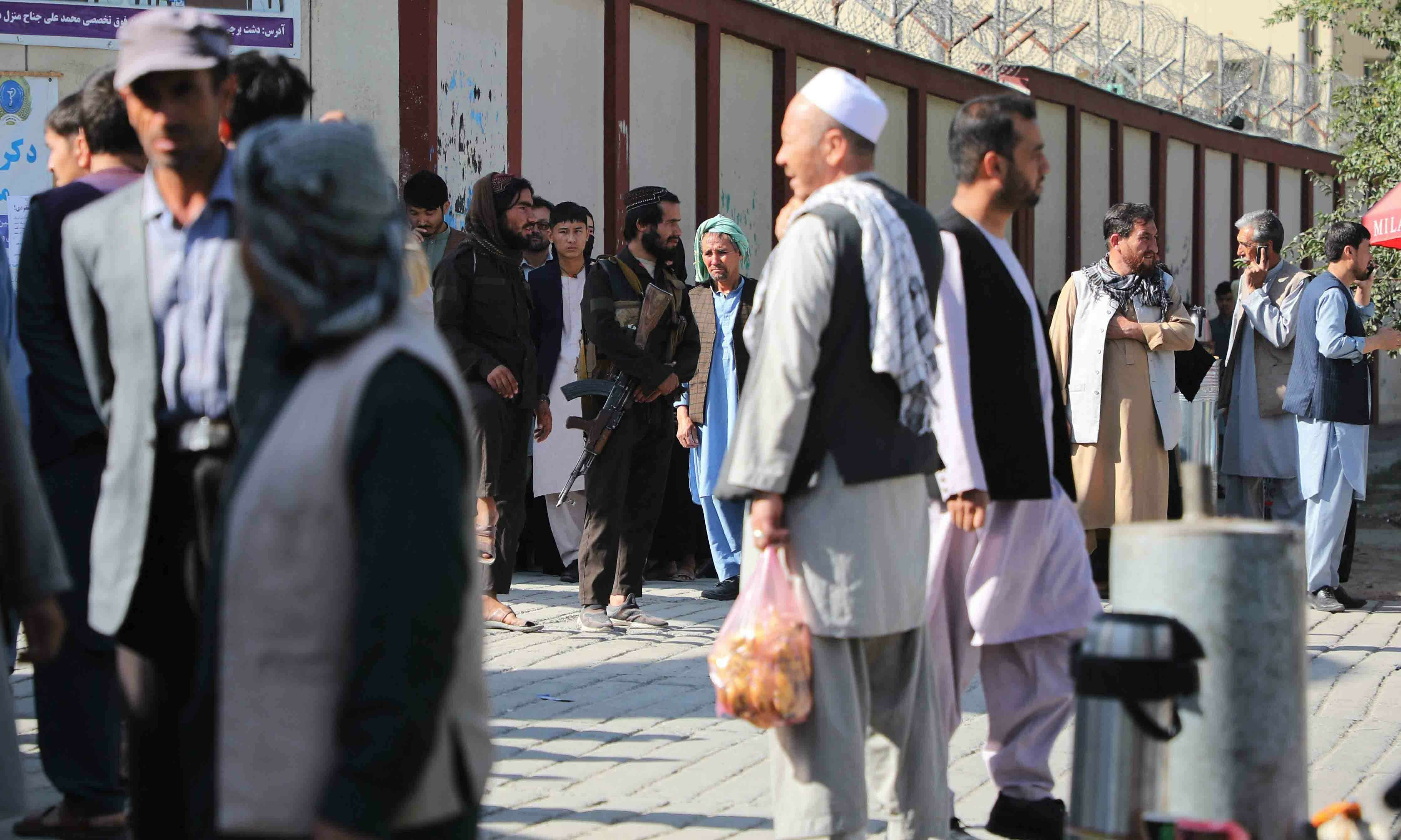 <p>Taliban fighters (C) stand guard as people gather to search for relatives outside a hospital in Kabul on September 30. — AFP</p>