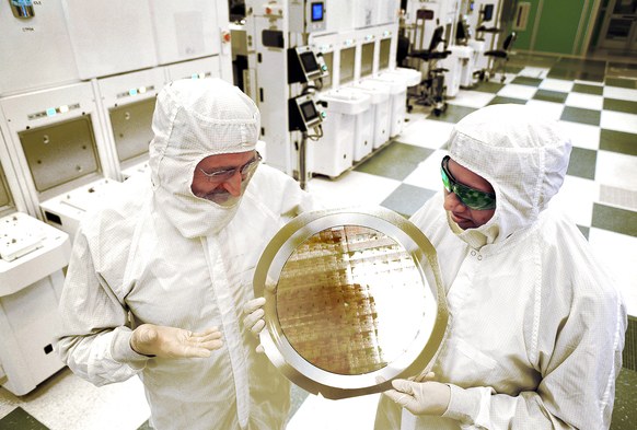Scientists in protective clothing hold up IBM's 7 nm chip wafer