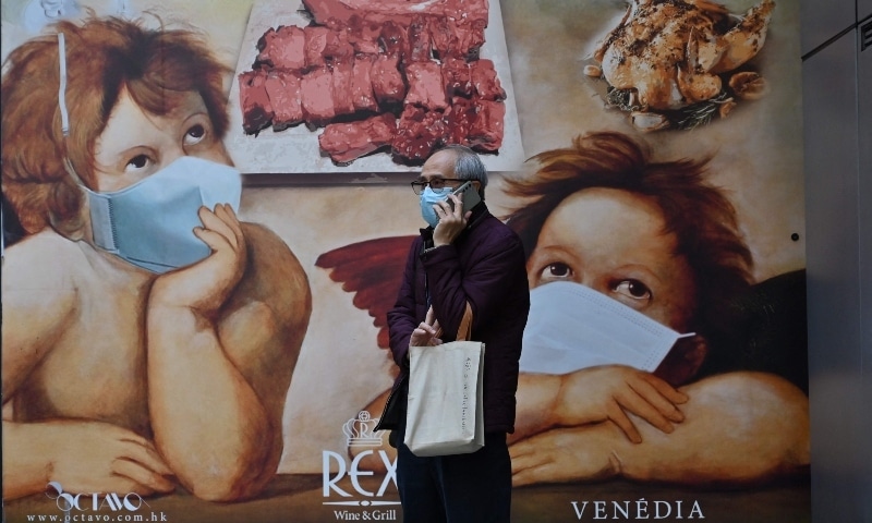 A man talks on the phone in front of a banner for a restaurant in Hong Kong on February 14. — AFP