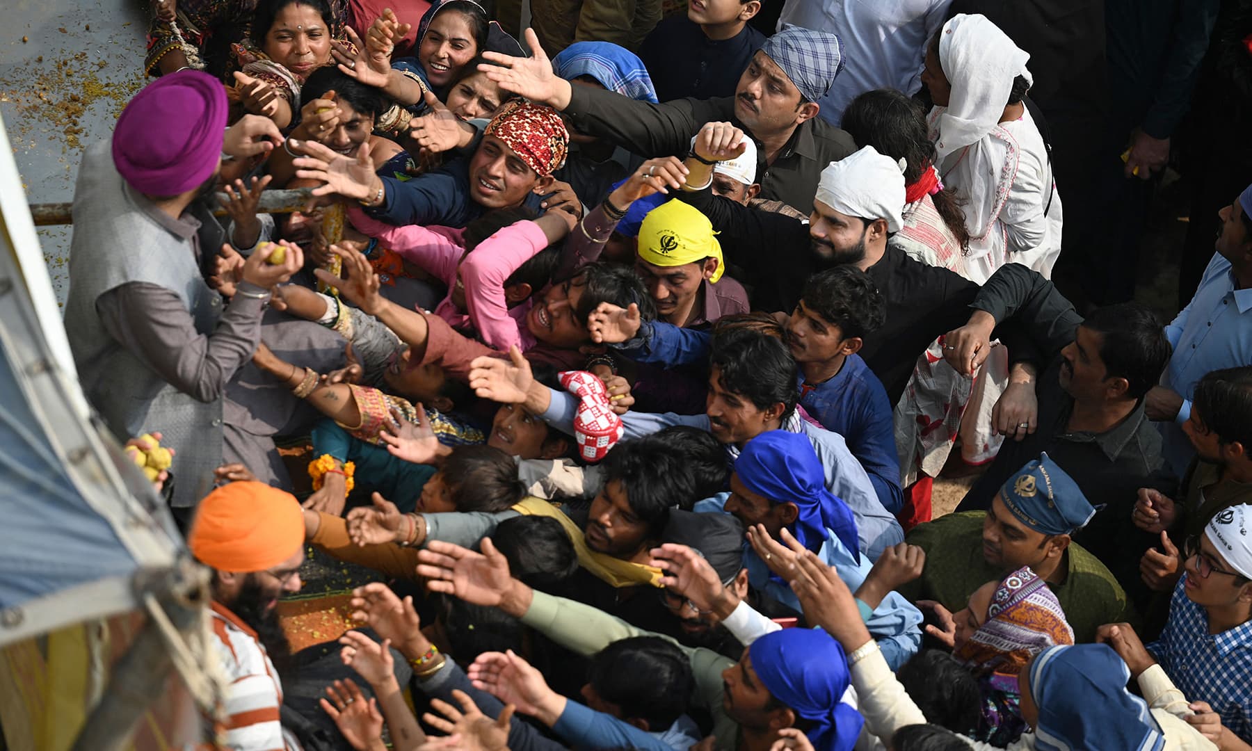Sikh pilgrims get sweets during a religious procession in Nankana Sahib on November 19. — AFP