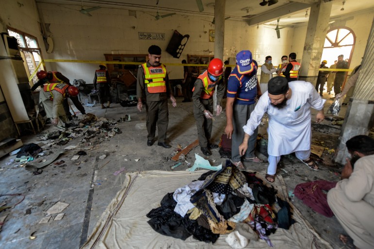 Rescue workers collect remains after a blast at a religious school in Peshawar [Abdul Majeed/AFP]