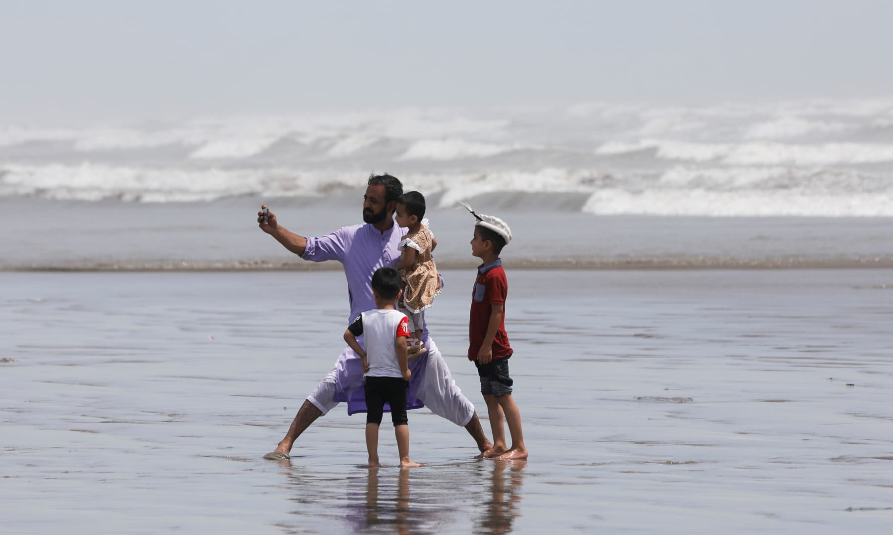 A man takes a selfie with his children while they visit Clifton beach in Karachi, August 10. — Reuters