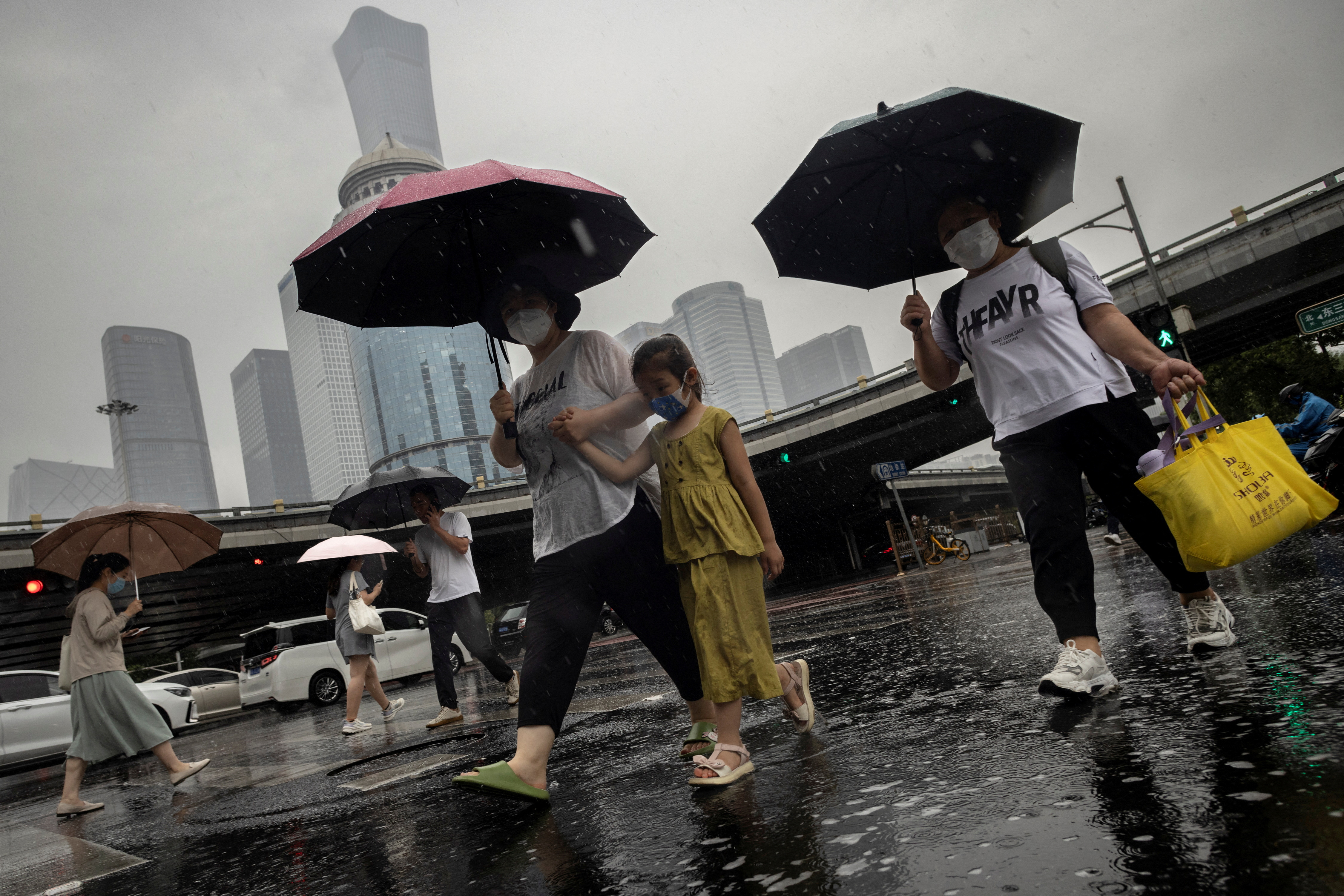 People walk in the Central Business District on a rainy day, in Beijing