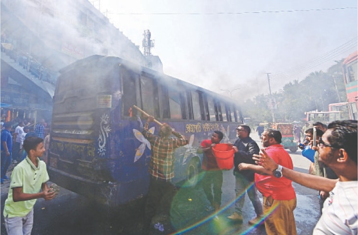 People try to douse a fire inside a bus allegedly torched by protesters during a nationwide transport blockade called by an opposition party, in Dhaka on Sunday.—AFP