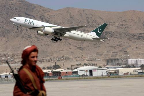 In this file photo a Taliban fighter stands guard as a Pakistan International Airlines plane, the first commercial international flight to land since the Taliban retook power last month, takes off with passengers onboard at the airport in Kabul on September 13, 2021.
