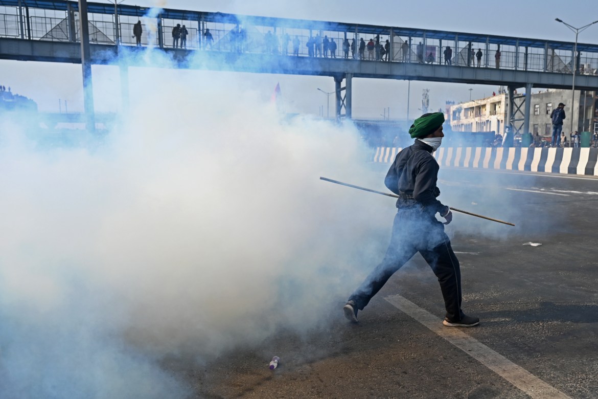 A farmer runs through tear gas fired by the police during a tractor rally as farmers protested against the government's recent agricultural laws. [Sajjad Hussain/AFP]