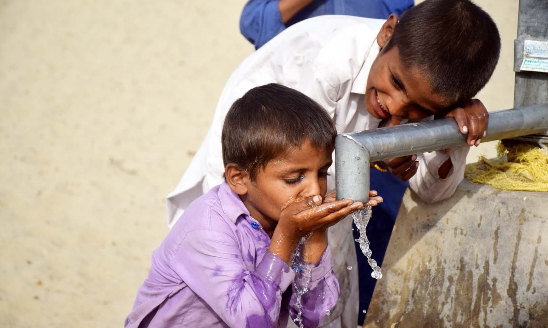 Children drinking water from a well in Achhro Thar, Khipro, Sindh. — Photo by Umair Ali