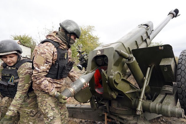 A Ukrainian soldier loads a projectile into a cannon.