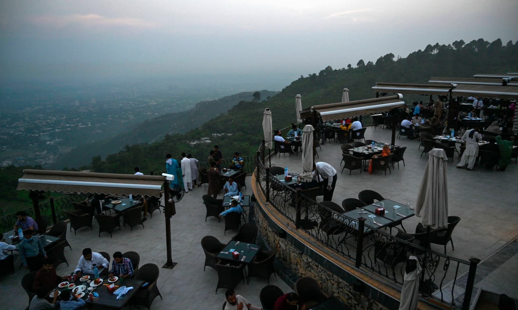 People eat at a rooftop restaurant on Margalla Hills in Islamabad on August 10, after government announced it would be lifting most of the country's remaining coronavirus restrictions. — AFP
