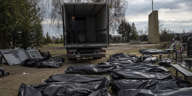 WARNING GRAPHIC IMAGE: A cemetery worker waits in a truck before colleagues start to load corpses of civilians killed in Bucha before transporting them to a morgue on the outskirts of Kyiv, Ukraine.