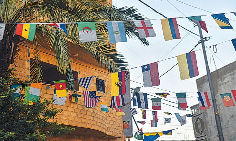 BUNTINGS of flags from teams competing in Fifa Cup adorn a lane in the village.—White Star