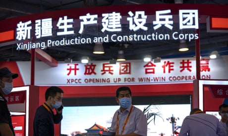 Staff members stand in front of a booth for the Xinjiang Production and Construction Corps (XPCC), a state-run authority that handles administrative, economic, and paramilitary functions in parts of western China's Xinjiang Uyghur Autonomous Region, at the China International Fair for Trade in Services (CIFTIS) in Beijing, Friday, Sept. 3, 2021. Chinese and foreign enterprises are showcasing their latest technology and services during the annual CIFTIS expo this week. (AP Photo/Mark Schiefelbein)