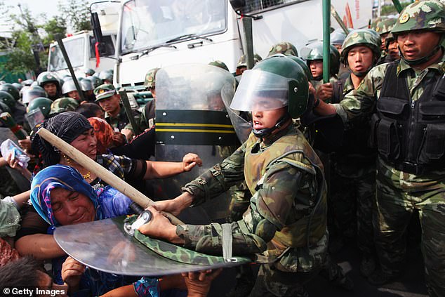 Chinese policemen push Uighur women who are protesting at a street on July 7, 2009 in Urumqi, the capital of Xinjiang Uighur autonomous region