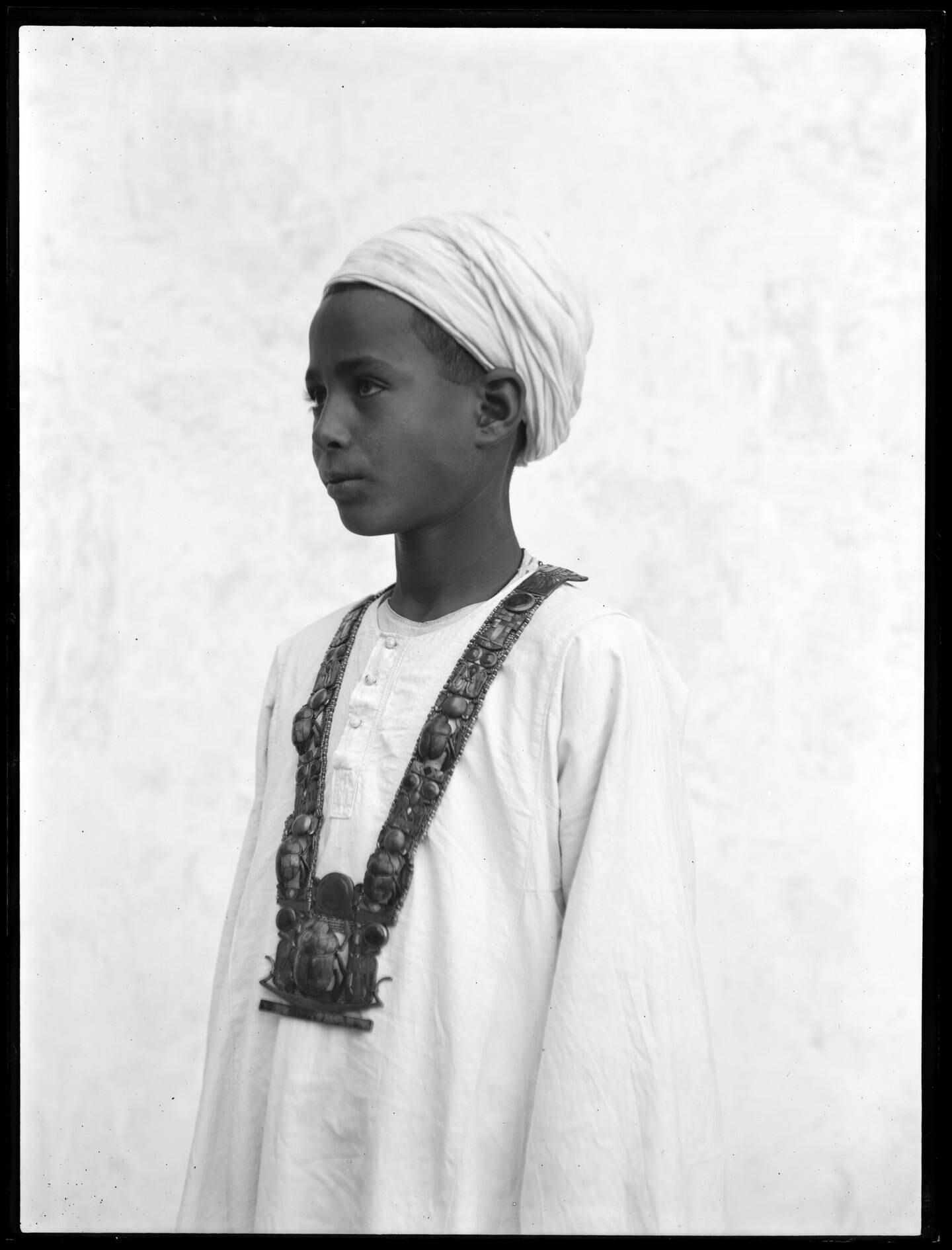 Photograph of an Egyptian boy wearing a heavy jewelled necklace from the tomb. Photo: Griffith Institute/University of Oxford