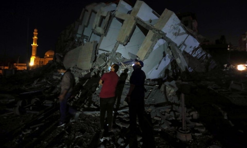 Palestinians look on as they stand at the site where a building was destroyed by Israeli air strikes amid a flare-up of Israeli-Palestinian violence, in Gaza City, May 11. — Reuters