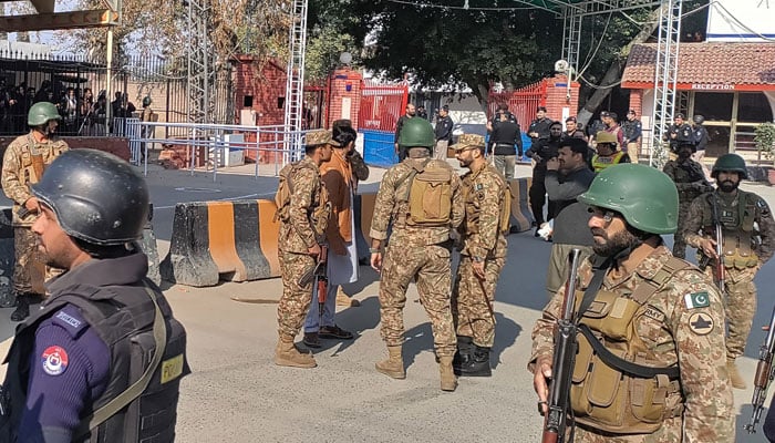 Security personnel stand guard outside the police headquarters after a blast in Peshawar on January 30, 2023. — AFP