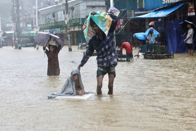 People wade through the water as they look for shelter during a flood, amidst heavy rains that caused widespread flooding in the northeastern part of the country, in Sylhet, Bangladesh, June 18, 2022. (Reuters)