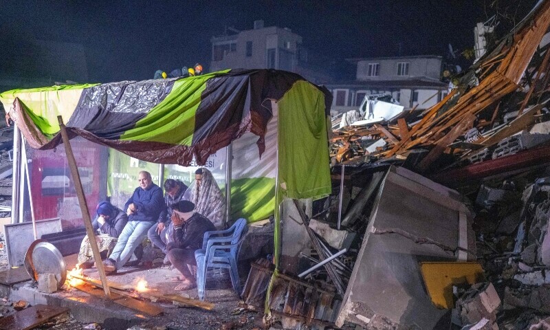 People take rest next to bonfire in the rubble in Hatay, after a 7.8-magnitude earthquake struck the country’s southeast on February 6, 2023. — AFP