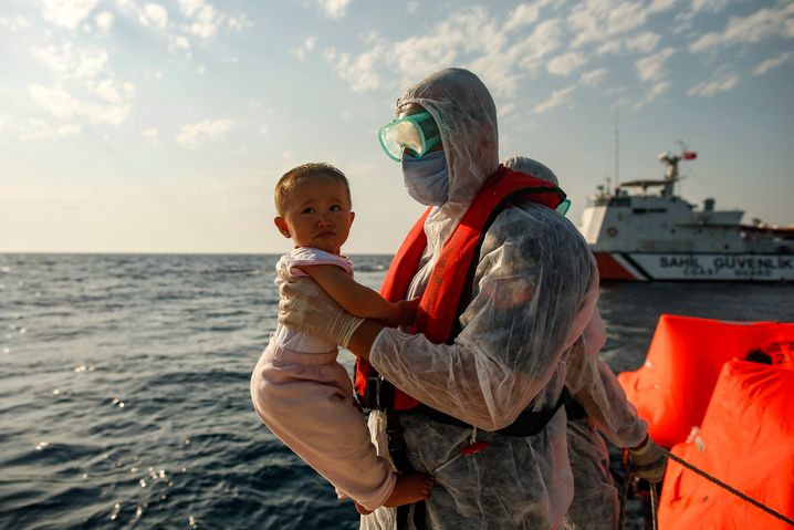 Left adrift on the high seas: A Turkish coast guard officer rescues a child from a life raft on the Aegean.