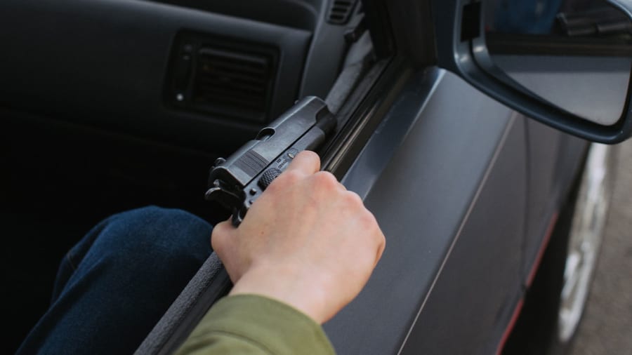 Stock image of person holding gun in a vehicle.
