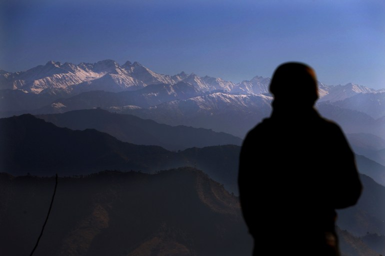 An Indian soldier looks towards the snow-covered Pir Panjal range in the Himalayas from a forward post at LoC between India and Pakistan, in Poonch, Indian-administered Kashmir [File: Channi Anand/AP]