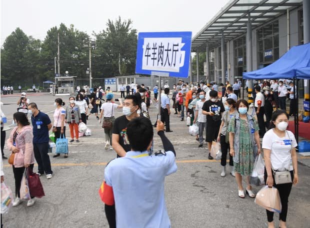 People emerging from quarantine line up for buses in Beijing, July 11, 2020.