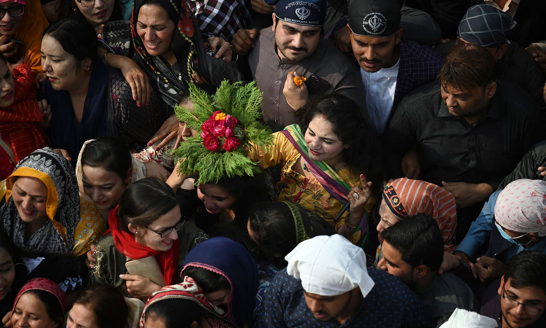 Sikh pilgrims gather around a bus (unseen) carrying the Guru Granth Sahib during a religious procession in Nankana Sahib on November 19. — AFP