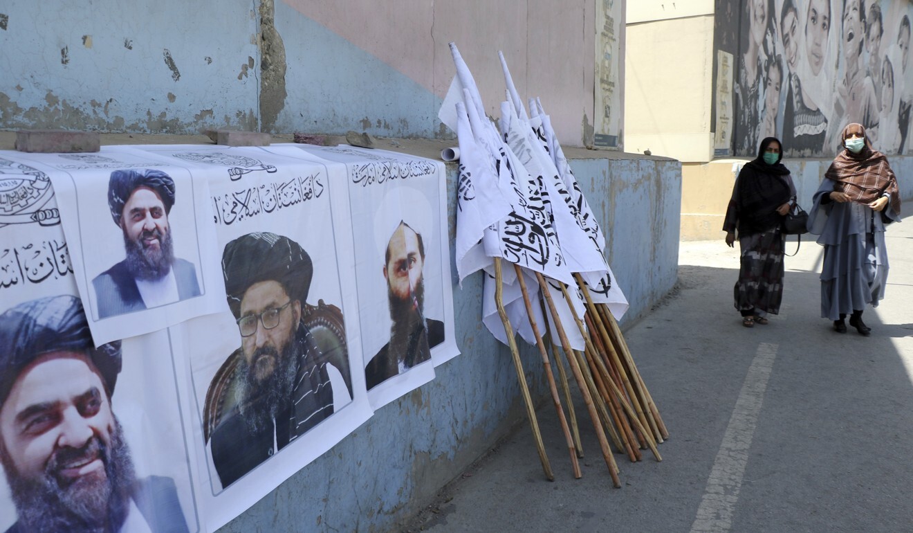 Afghan women pass posters of Taliban leaders and flags in Kabul. Photo: AP