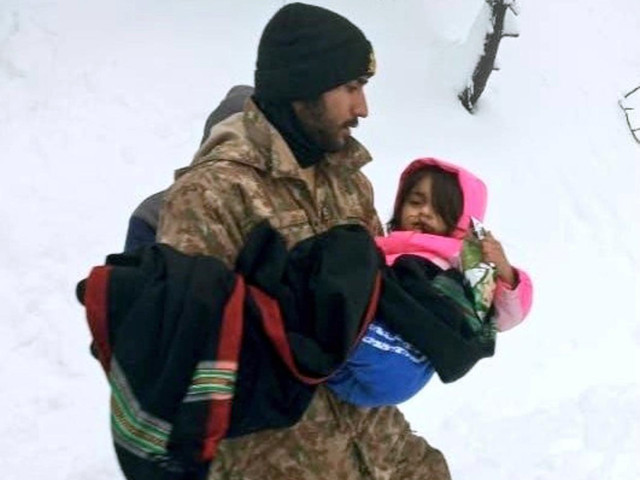 a soldier shifting children to an army relief camp established in murree division photo ispr