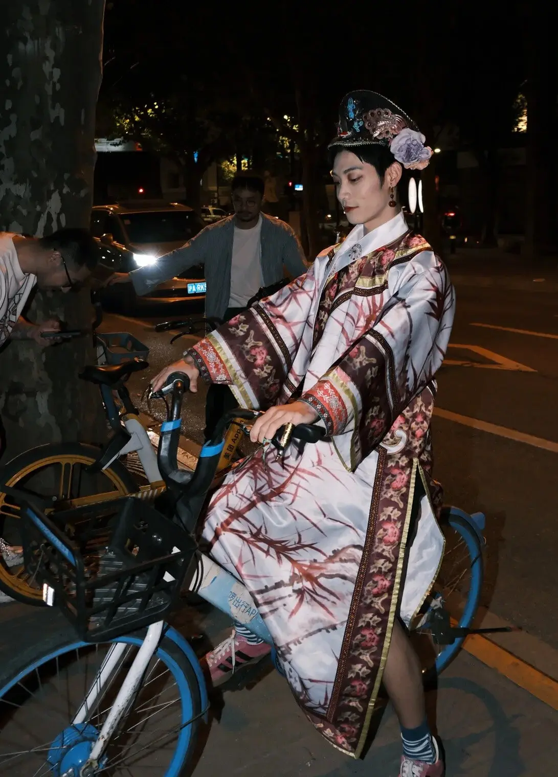 A man dressed up as an ancient Chinese royal concubine riding a bike.