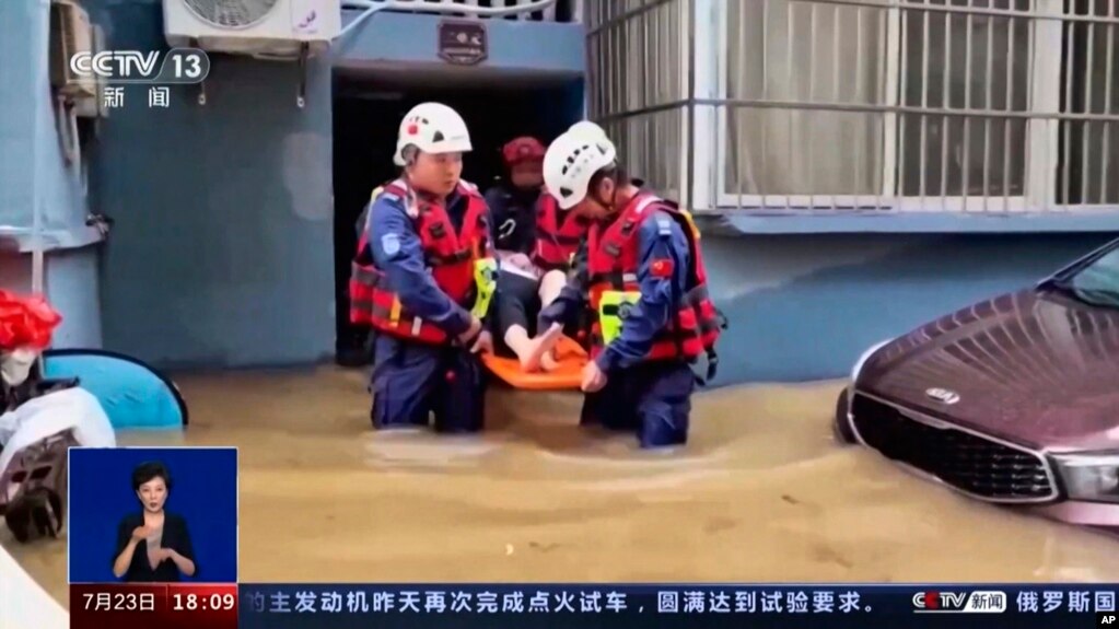 In this image taken from video footage run by China's CCTV, rescuers evacuate a resident following flooding in a village in eastern China's Zhejiang province, July 23, 2023. (CCTV via AP)